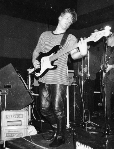 BASH OUT THE ODD live October, 1989 at The Bull & Gate in  Kentish Town, London. Mark Mortimer with, in the background, the brass section, Bryan Hurdley (left, rear), Mark Allison (right, rear).  Not pictured was Martin Cooper.